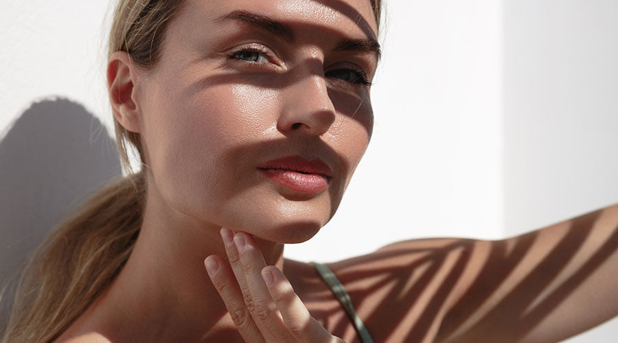 Femme au teint lumineux protégée du soleil, symbolisant l’éclat naturel d’une peau équilibrée grâce aux soins visage bio IUM.