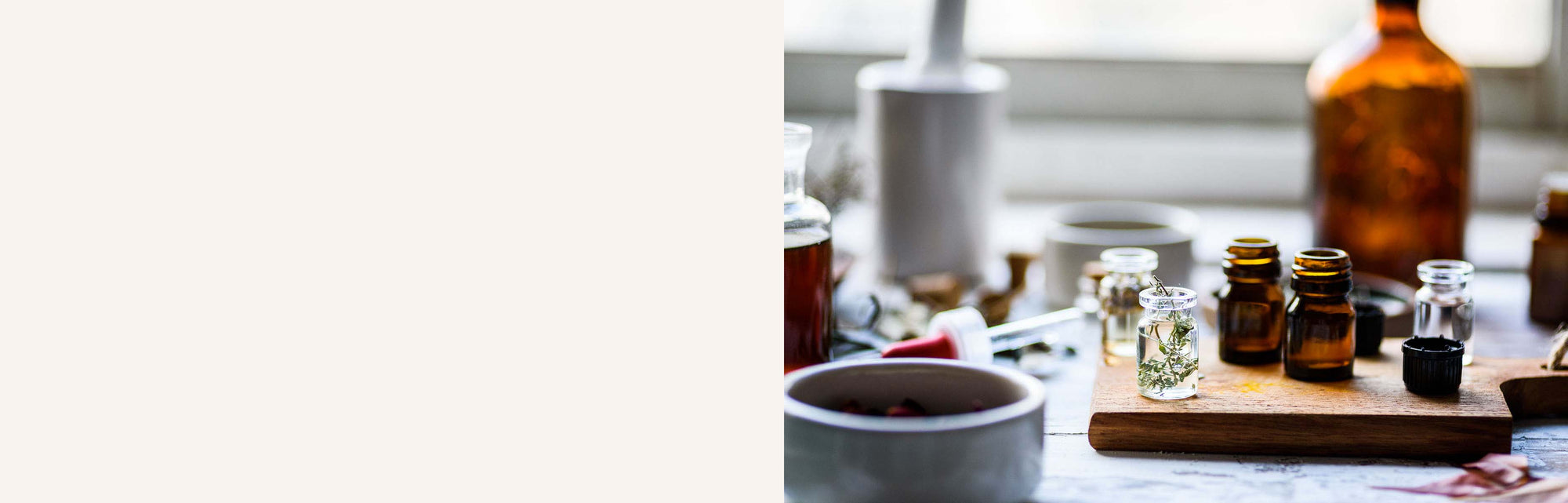 bannière table avec des petits flacons d'huiles essentielles et de plantes, fond beige