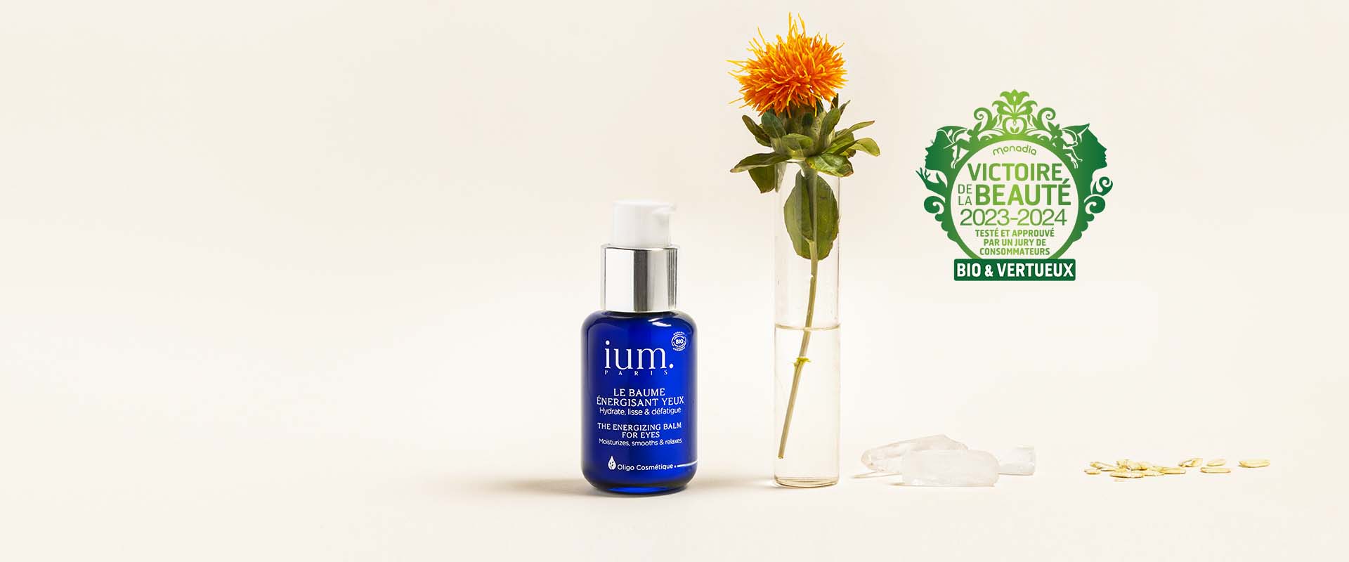 Blue bottle of ium energizing eye balm on beige background with safflower in test tube