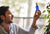 Man holding blue ium bottle on beige background and plants