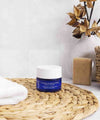 Blue pot of ium exfoliating mask in luminous bathroom with beige accessories