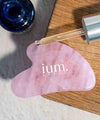 gua sha face massage stone in pink qurtz with ium plumping serum seen from above